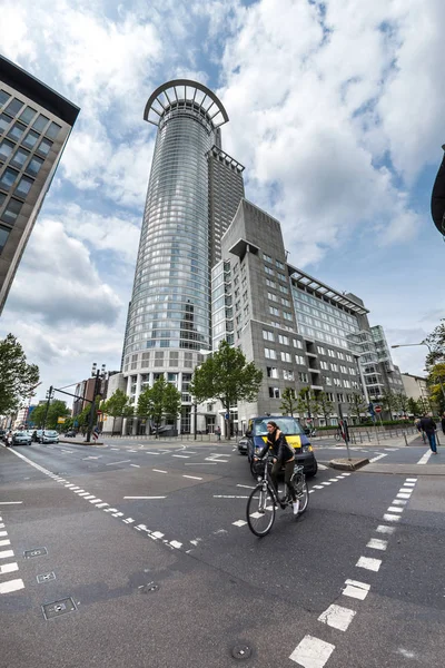 Mulher em uma bicicleta com altos edifícios de escritórios no fundo Fotos De Bancos De Imagens