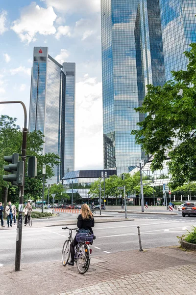 Kvinna på en cykel med höga kontorsbyggnader i bakgrunden — Stockfoto