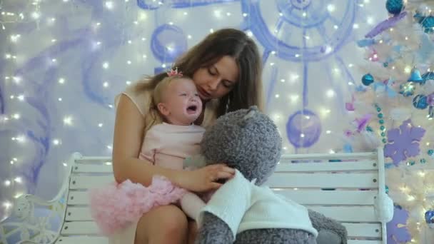 Mom and little girl play with bear sitting on the bench — Stock Video