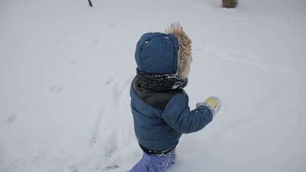 Liten pojke löper genom snö slow motion — Stockvideo