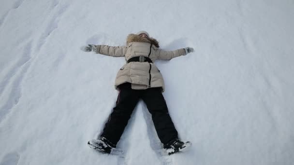 Girl playing in the snow angel — Stock Video