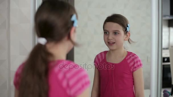 A kislány azt mutatja, hogy arcát a tükör előtt — Stock videók