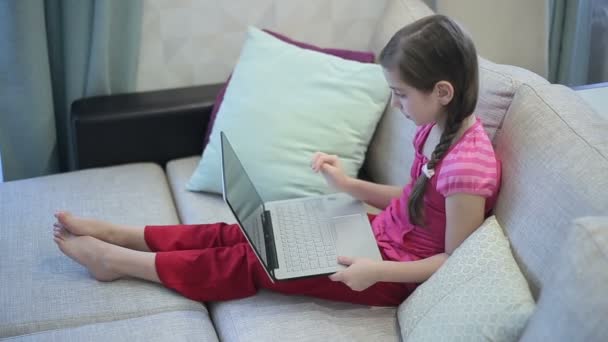 A girl on the sofa is education on a laptop — Stock Video