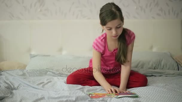 Дівчина на ліжку читає книгу — стокове відео