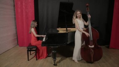Müzik aletleri oynayan iki kız. Piyano ve doublebass