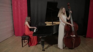 Müzik aletleri oynayan iki kız. Piyano ve doublebass