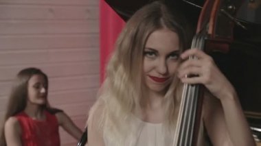 Müzik aletleri oynayan iki kız. Piyano ve doublebass