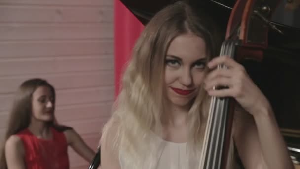 Two girls playing musical instruments. Piano and doublebass — Stock Video