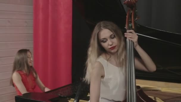 Two girls playing musical instruments. Piano and doublebass — Stock Video