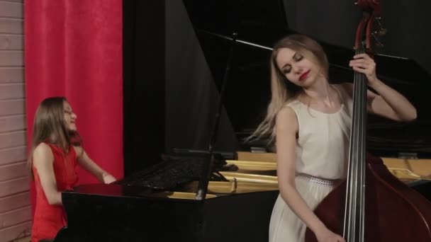 Two girls playing musical instruments. Piano and doublebass — Stock Video