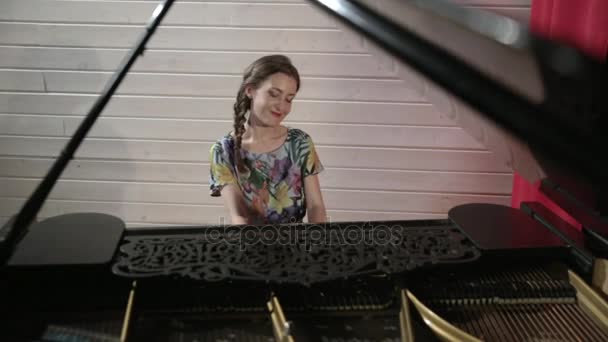 Mujer joven en vestido de color tocando en el piano — Vídeo de stock