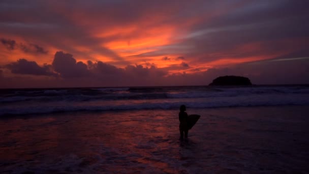 Silueta de mujer hermosa con tabla de surf durante la puesta del sol increíble — Vídeo de stock