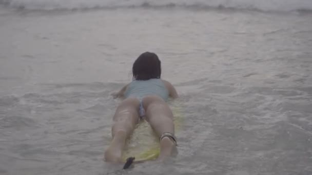 Женщина с желтой доской для серфинга на пляже — стоковое видео