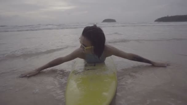 Красива жінка з жовтим дошкою для серфінгу на пляжі — стокове відео
