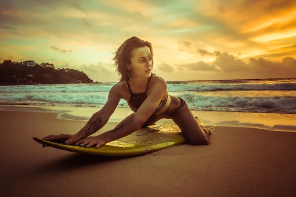 Beautiful woman with yellow surfboard on the beach over amazing sunset — Stock Photo, Image