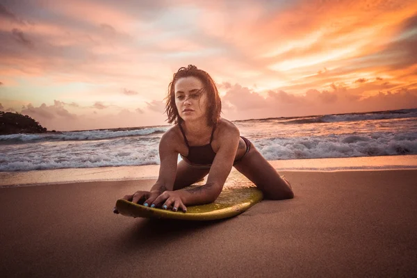 Schöne Frau mit gelbem Surfbrett am Strand bei herrlichem Sonnenuntergang — Stockfoto