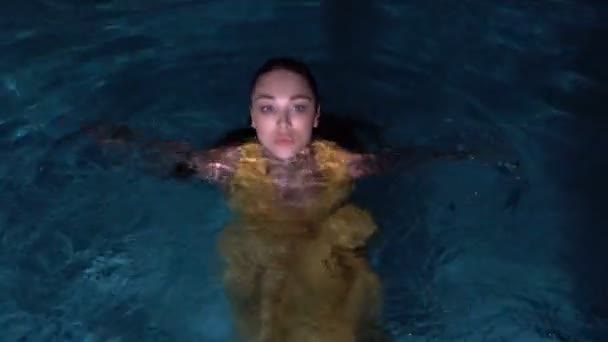 Yüzme havuzunda sarı elbise giyen güzel esmer kadın — Stok video