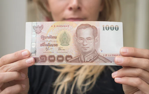 Closeup of 1000 Thai Baht note withdrawn from ATM over blurred woman's face — Stock Photo, Image