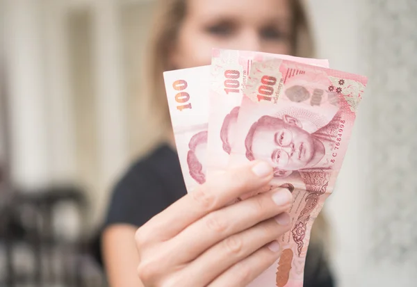 Крупный план 100 банкнот Тай Бат снятых из банкомата на лицо размытой женщины — стоковое фото