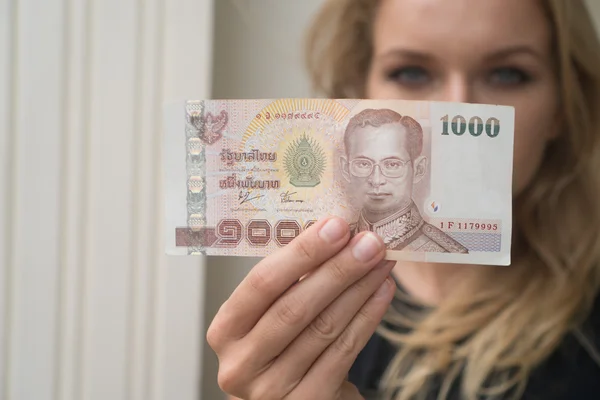 Closeup of 1000 Thai Baht note withdrawned from ATM over blurred woman's face — Stock Photo, Image