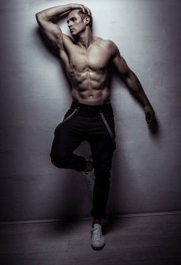 Kaslı sporcu genç adam ışık gri duvardan poz