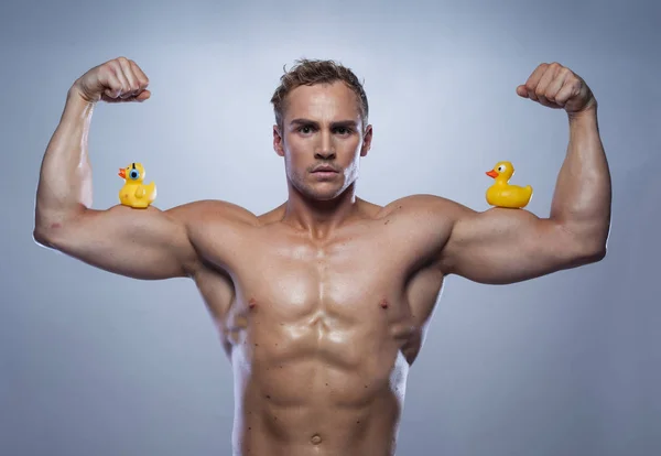 Kaslı sporcu genç adam onun pazı üzerinde lastik ördek ile poz — Stok fotoğraf