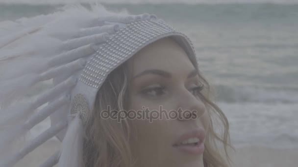 Mujer con sombrero indio de plumas blancas en la playa — Vídeos de Stock