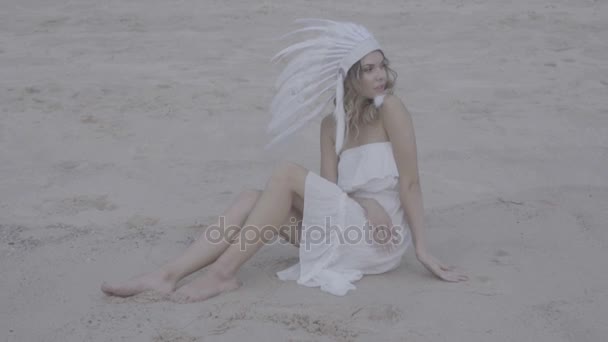 Donna con cappello indiano piuma bianca in spiaggia — Video Stock