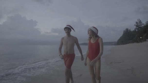 Couple wearing santa hat at the beach — Stock Video
