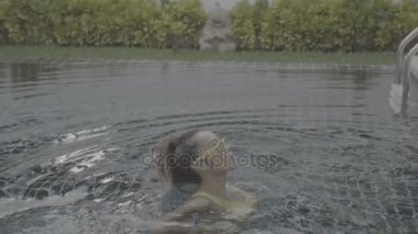 Yüzme havuzunda sarı mayolu seksi bir kadın.