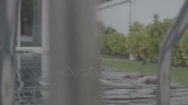 Yüzme havuzunda sarı mayolu seksi bir kadın.