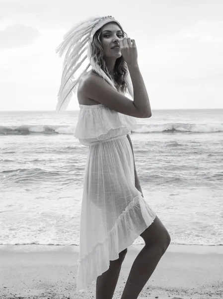 Frau mit Indianerhut mit weißer Feder am Strand — Stockfoto