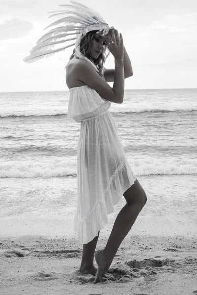 Vrouw met witte veren indiaanse hoed op het strand — Stockfoto