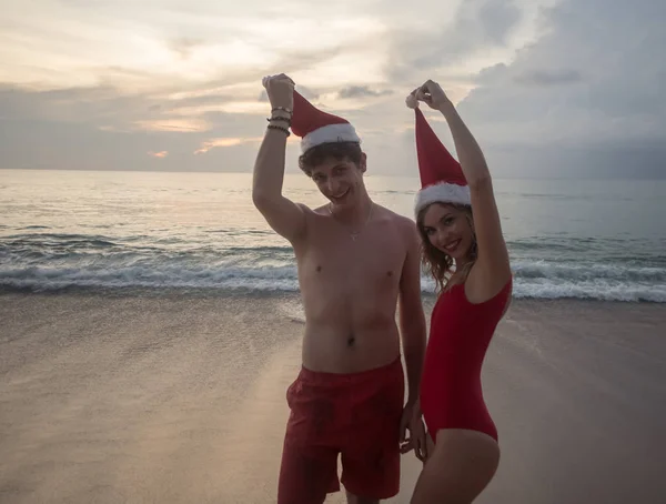 Casal usando chapéu de Papai Noel na praia — Fotografia de Stock