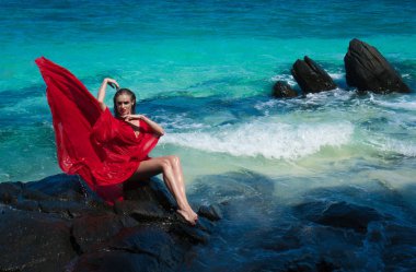 Kayanın üzerinde Kırmızı elbiseli kadın