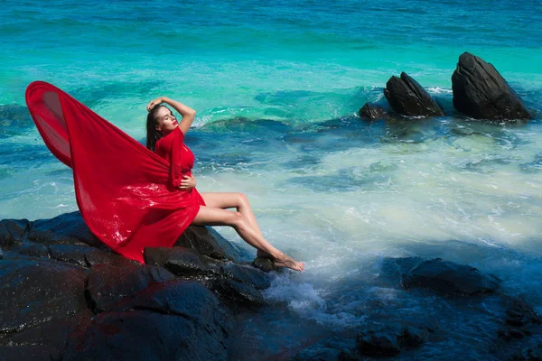 Жінка в червоній сукні на скелі — стокове фото