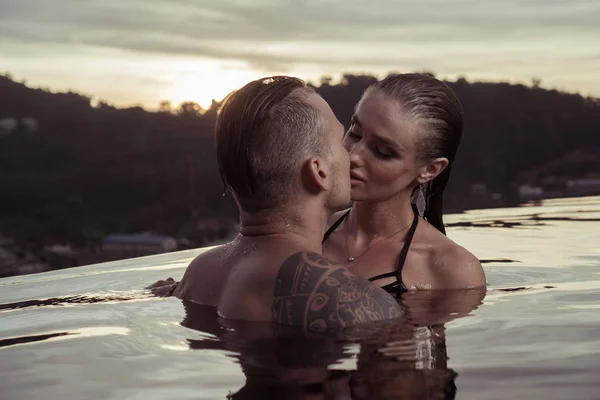 Romantic couple alone in infinity swimming pool — Stock Photo, Image