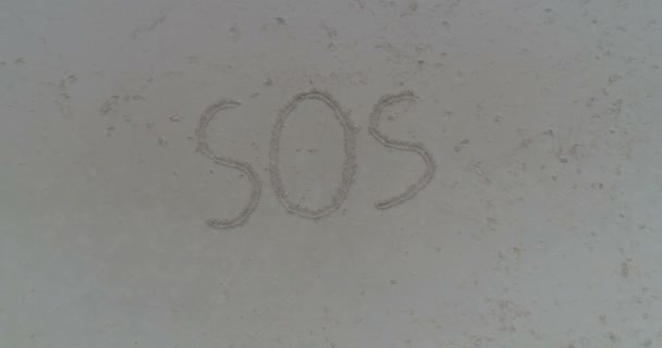 Висхідний повітряний постріл SOS написаний на піску на тропічному пляжі — стокове відео
