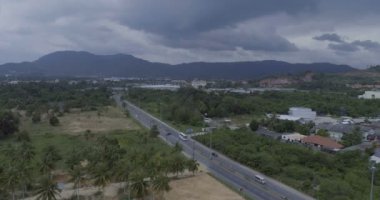 Dağlar ve gökyüzü artalanları içinde Kathu, Phuket ile yol ve palmiye ağaçlarının havadan görünümü