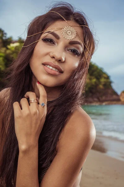 美丽的黑发女人，与金头饰品微笑在海面热带背景的特写肖像 — 图库照片