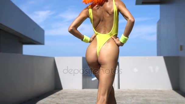 Kvinna i gula baddräkt och orange peruk — Stockvideo