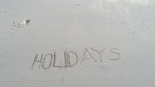 "Férias "escrito na areia na praia. Conceito de férias de viagem — Fotografia de Stock