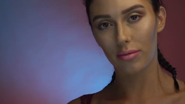 Closeup tvář hezká žena v burgundské prádlo s copánky lodě na kameru ve studiu — Stock video