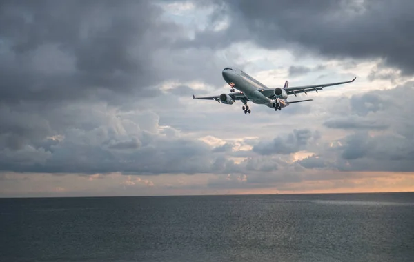 Avion volant au-dessus de la mer au-dessus du ciel nuageux — Photo