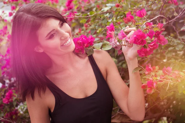 Szép nő, rózsaszín virágok között — Stock Fotó