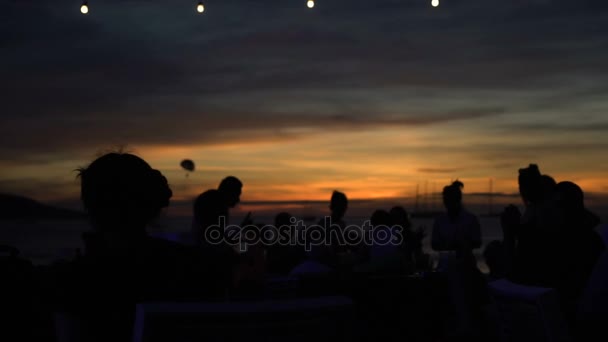 Silhouettes of people hanging out at the beach club during beautiful sunset — Stock Video