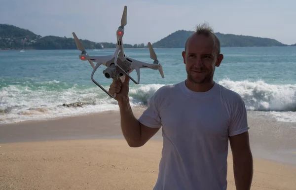 Homme heureux avec caméra drone dans ses mains sur la plage — Photo