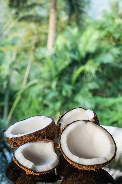 Cocos en la mesa de vidrio negro aislados sobre fondo de palmeras borrosas —  Fotos de Stock