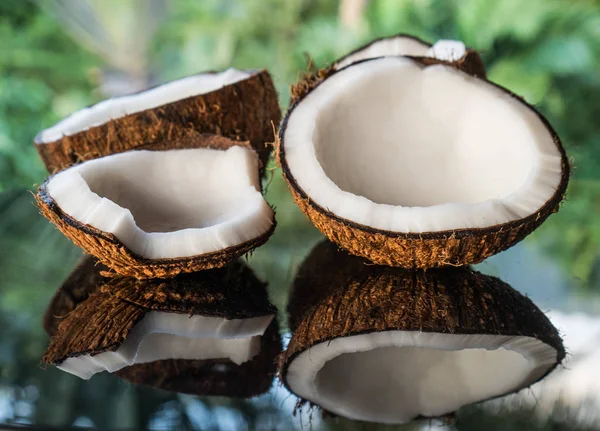 Cocos en la mesa de vidrio negro aislados sobre fondo de palmeras borrosas —  Fotos de Stock