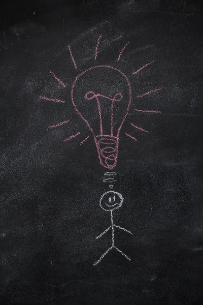 Symbol of human with ligh bulb above head on black chalkboard — Stock Photo, Image